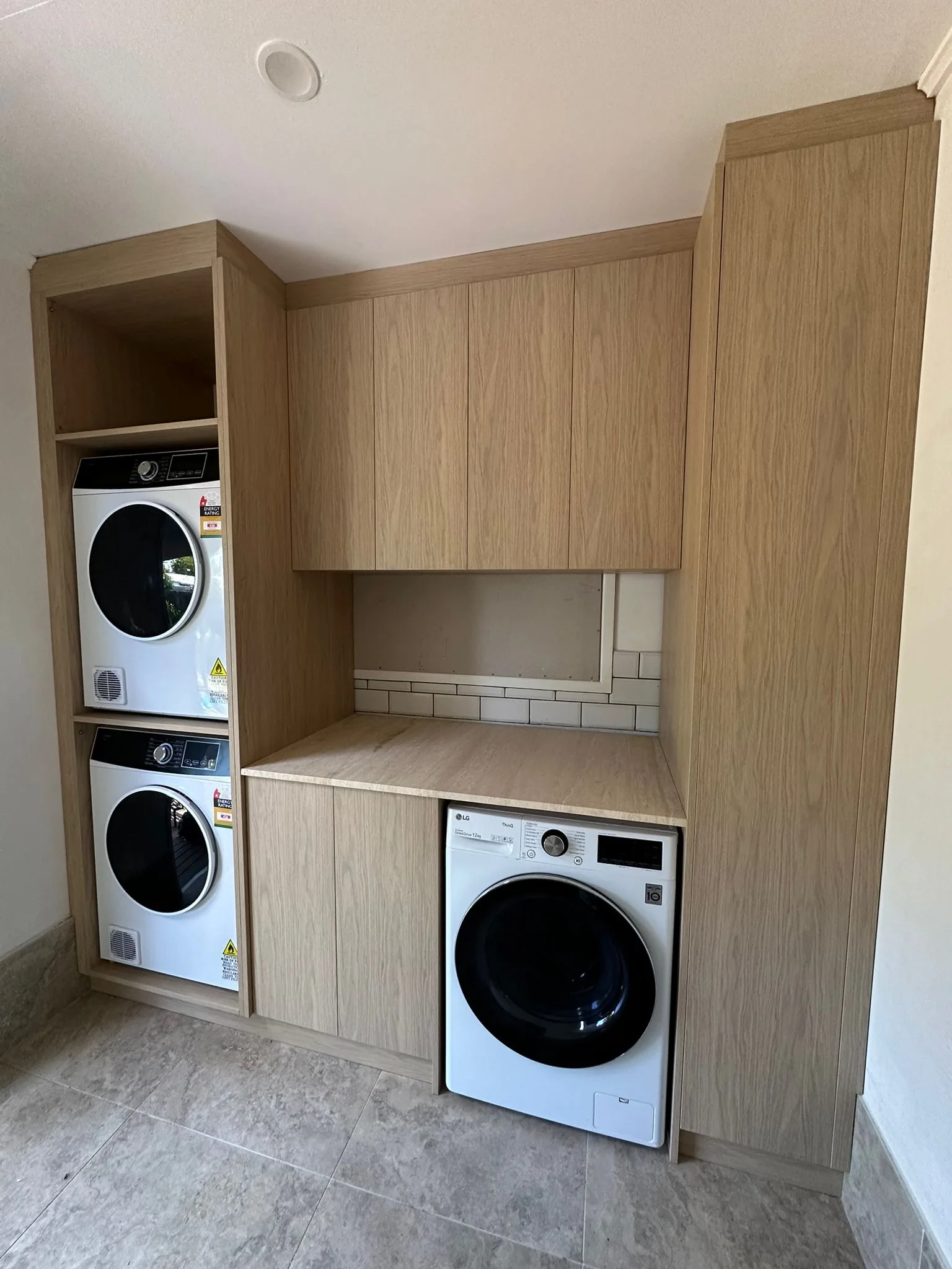 Laundry with stacked washer and dryer in oak cabinetry