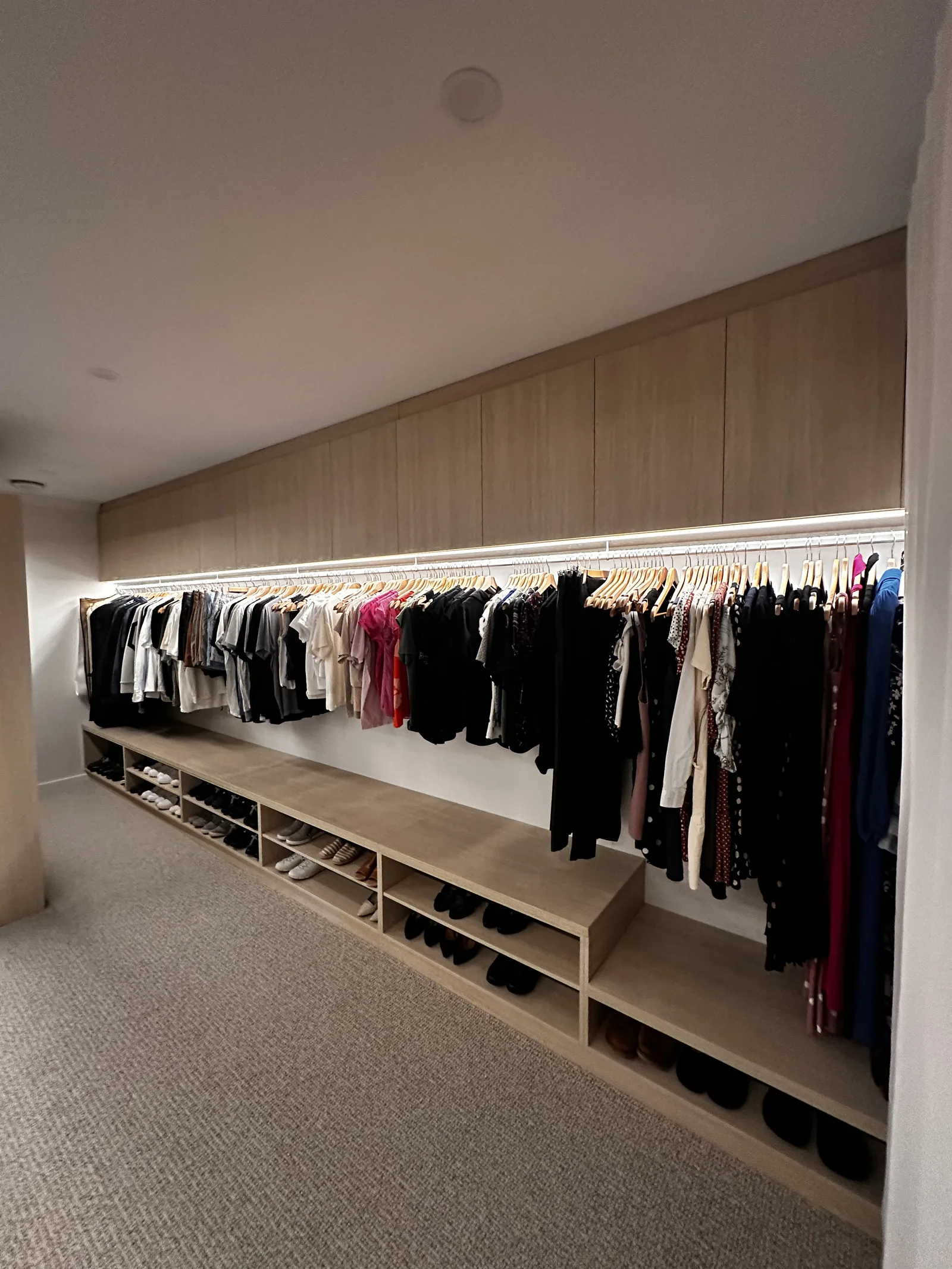 Walk-in robe with full-length lit oak hanging rail and shoe shelving